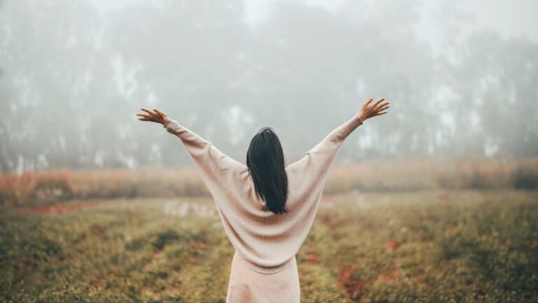 A woman standing quietly in nature, reflecting in solitude — symbolizing the non-linear journey of grief and healing.